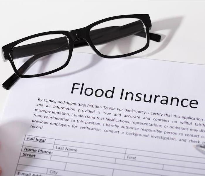 Flood insurance application on table with eye glasses